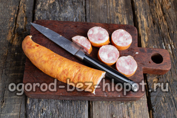 Die geräucherte Wurst in Stücke schneiden